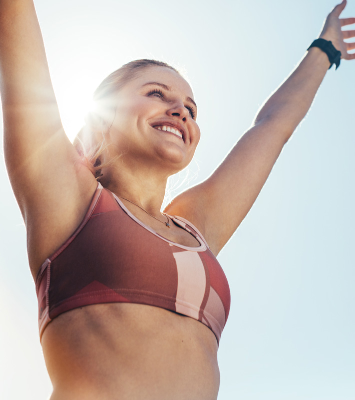 Smiling fitness woman doing workout raising her arms